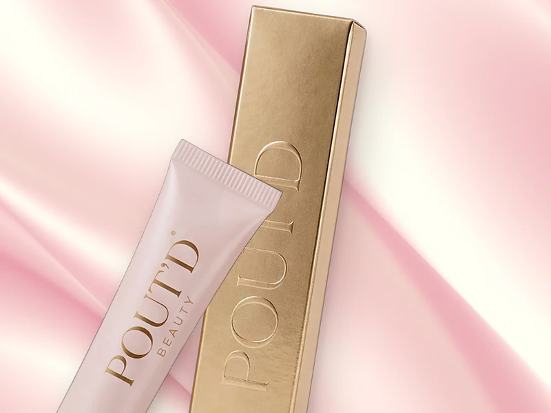 Close-up of the Pout'd Lip Plumper tube and gold box, a glossy plumper for fuller-looking thin lips